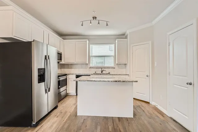 a kitchen with a sink cabinets stainless steel appliances and a window