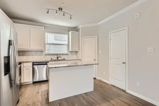 a kitchen with stainless steel appliances granite countertop white cabinets a sink and dishwasher with wooden floor