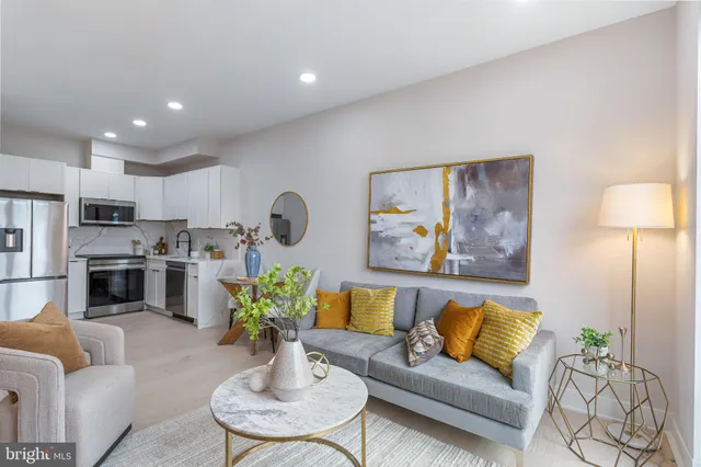 a living room with furniture potted plant and kitchen view
