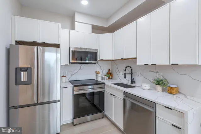 a kitchen with stainless steel appliances granite countertop a refrigerator stove a sink and dishwasher with white cabinets