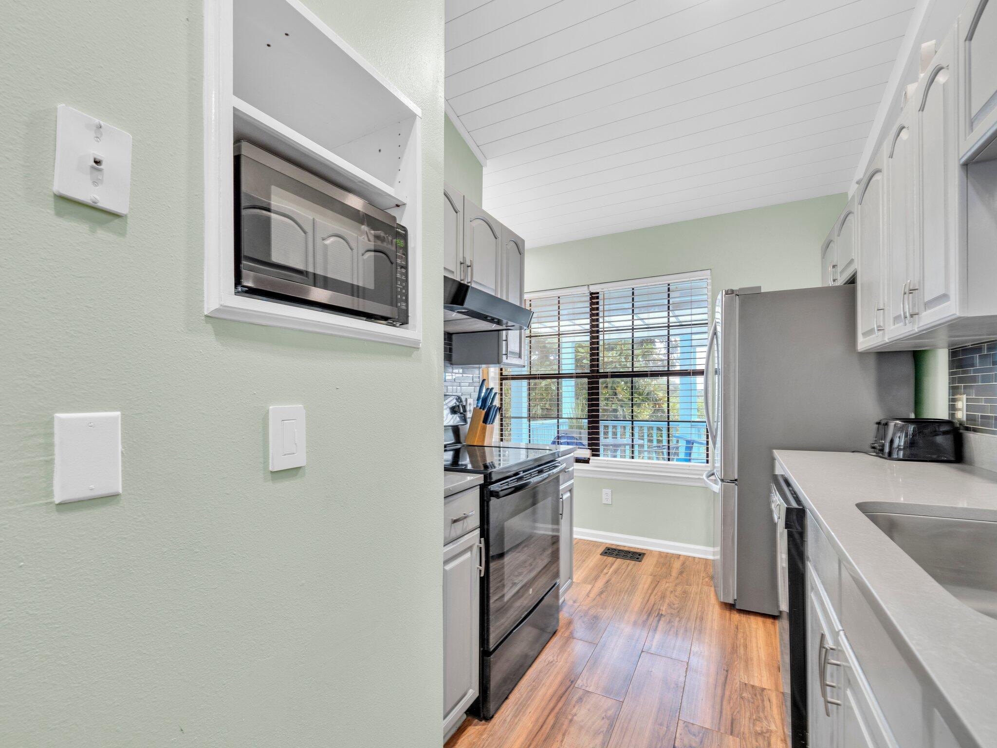 50 Gossamer Lane, Unit 10 Inlet Beach, FL 32461 - Photo 30 of 46 a kitchen with granite countertop a stove top oven a sink a refrigerator and wooden floor