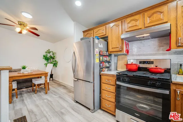 a kitchen with stainless steel appliances a stove a refrigerator and a dining table with wooden floor