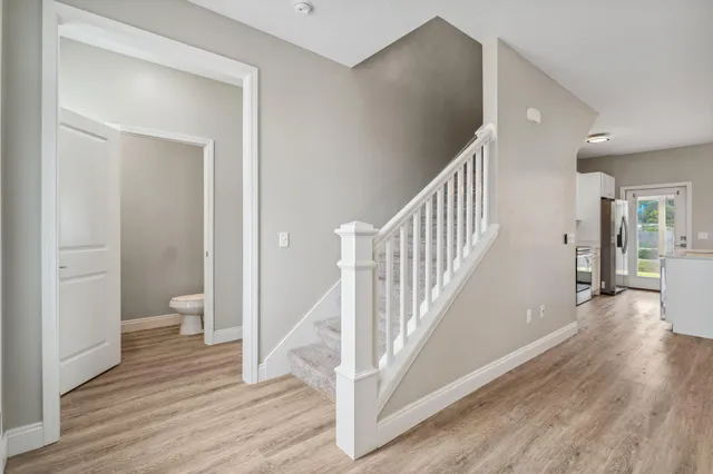 a view of a hallway with wooden floor and a bathroom