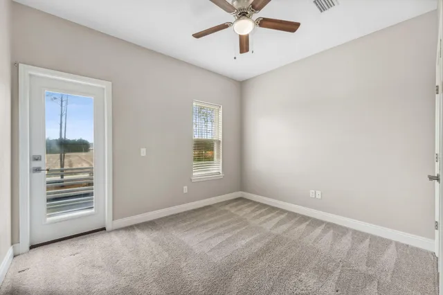 an empty room with windows and fan