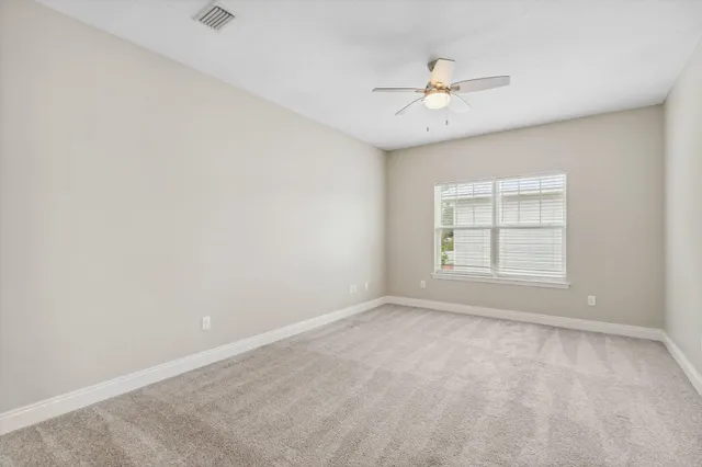an empty room with a window and a fan