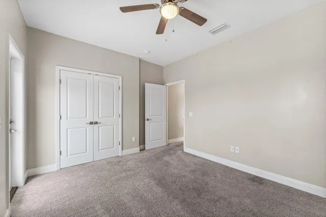 a view of an empty room and chandelier fan