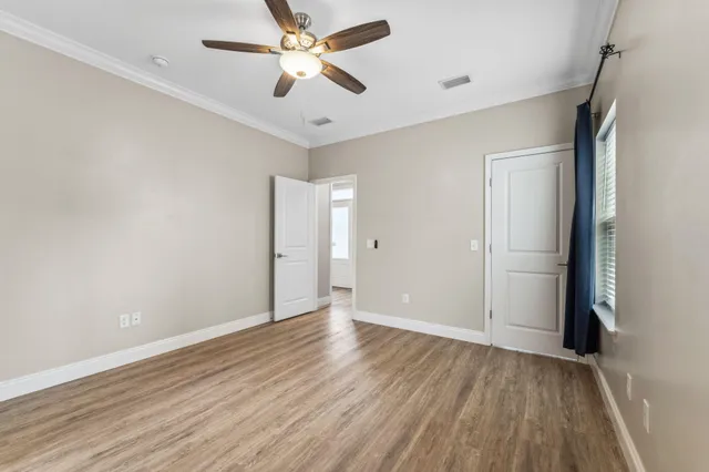 an empty room with wooden floor and a ceiling fan