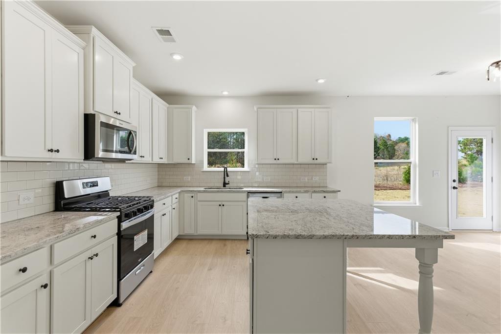373 Waterbluff Drive Southwest Mableton, GA 30126 - Photo 5 of 21 a kitchen with granite countertop white cabinets a sink a window and stainless steel appliances