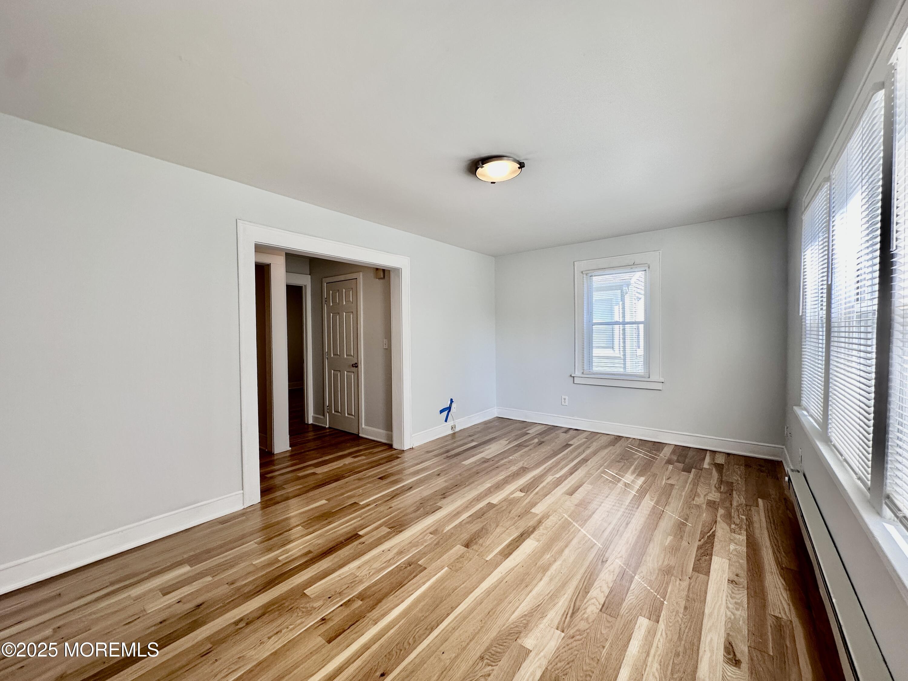 1004 5th Avenue, Unit 1N Asbury Park, NJ 07712 - Photo 2 of 14 a view of an empty room with wooden floor and a window