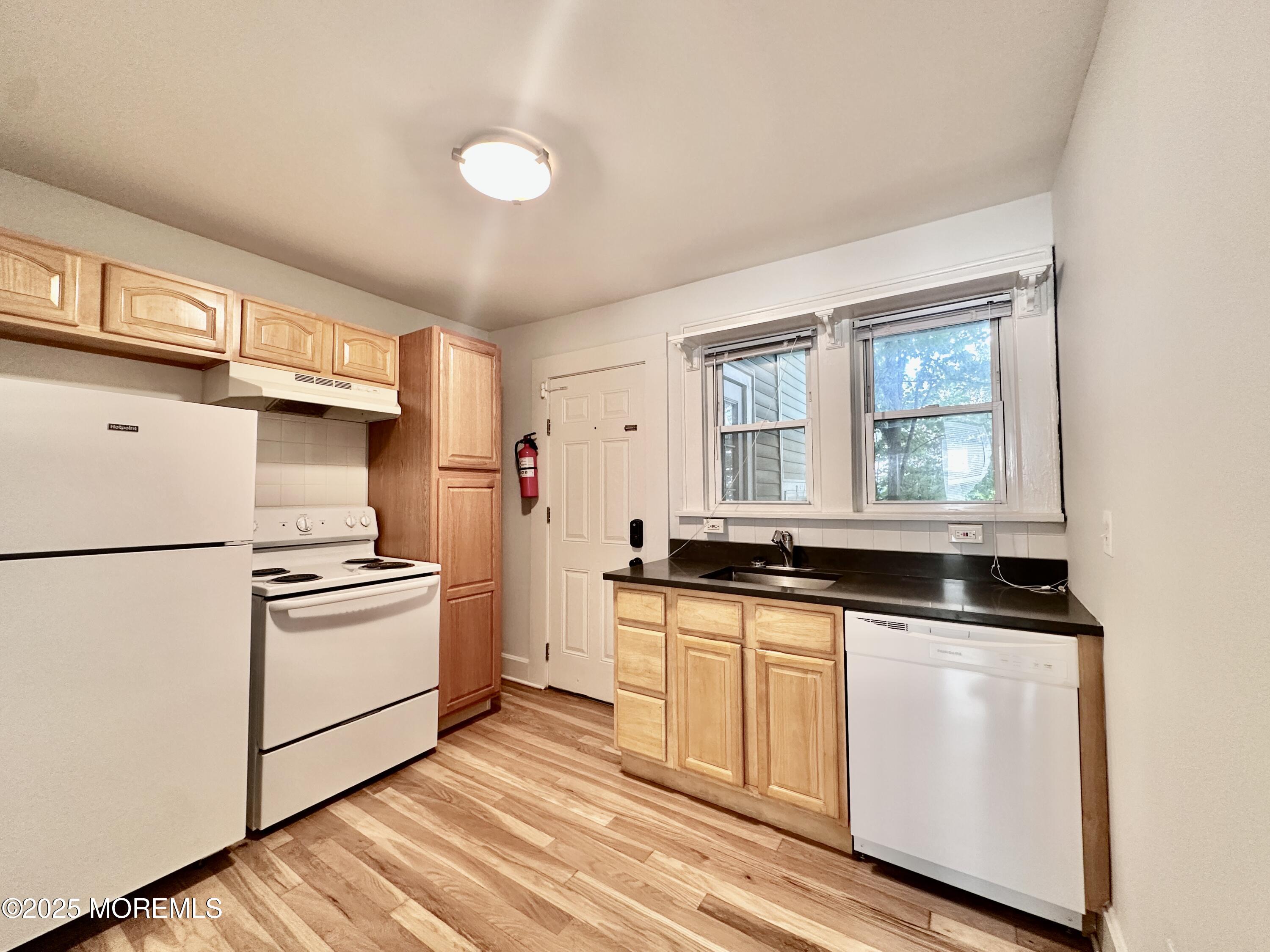 1004 5th Avenue, Unit 1N Asbury Park, NJ 07712 - Photo 9 of 14 a kitchen with granite countertop white cabinets and white appliances