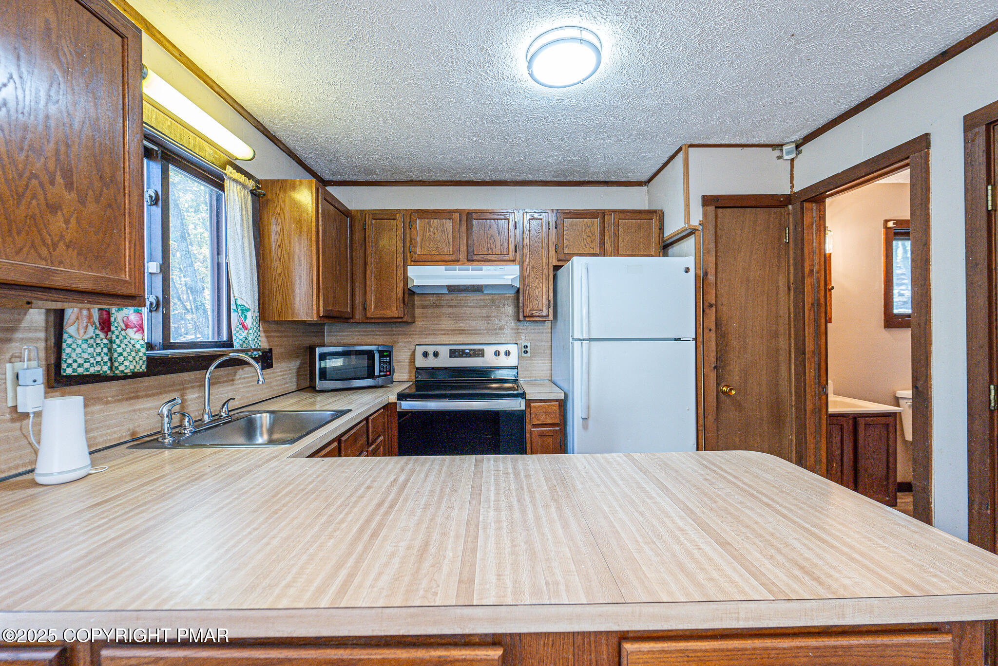 1562 Oak Lane Bushkill, PA 18324 - Photo 8 of 27 a kitchen with a refrigerator a stove a sink dishwasher and wooden cabinets with wooden floor
