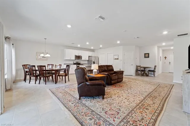 a living room with furniture a kitchen view and a large window