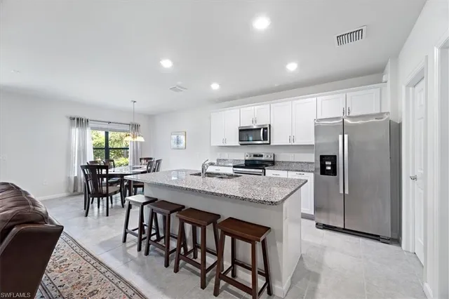 a kitchen with kitchen island granite countertop a table chairs microwave and refrigerator