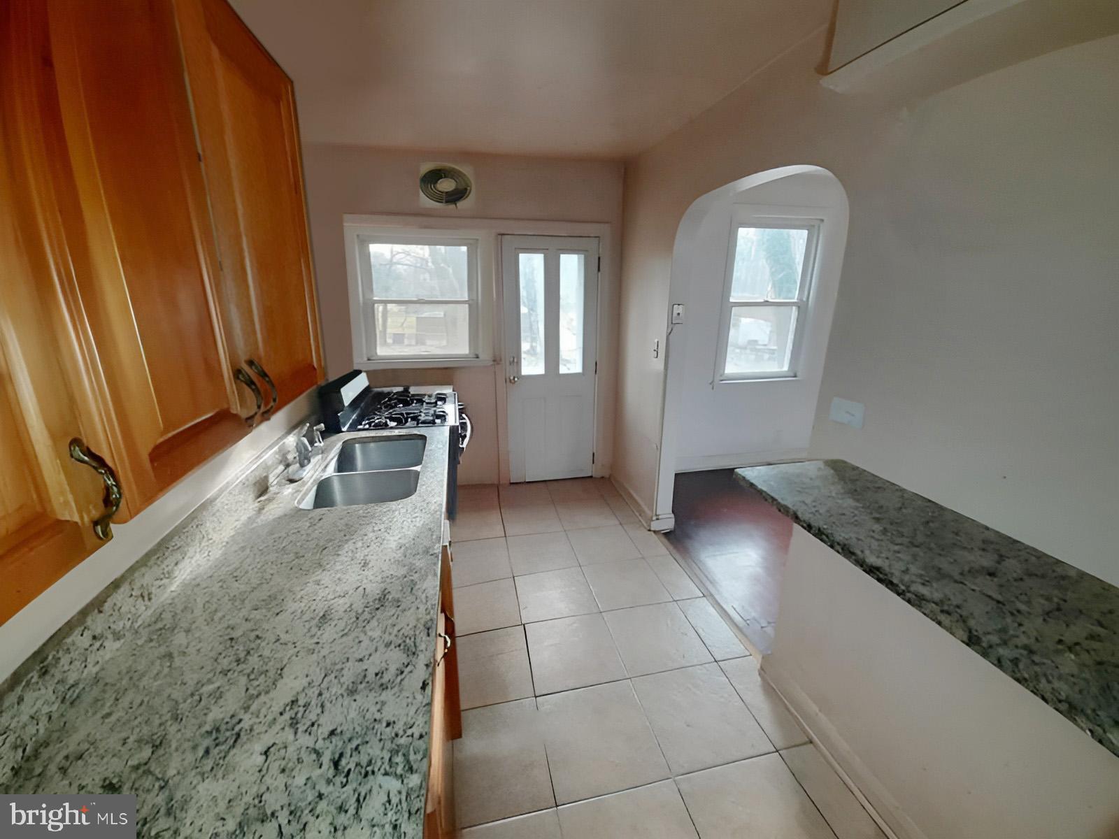 5619 Wesley Avenue Baltimore, MD 21207 - Photo 10 of 39 a kitchen with granite countertop a sink a stove top oven and cabinets