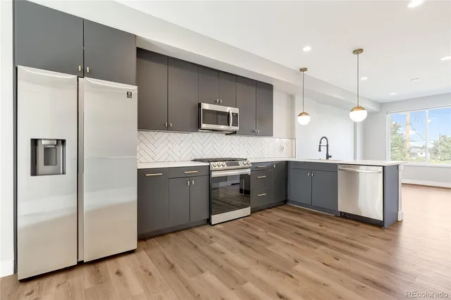 a kitchen with stainless steel appliances kitchen island granite countertop a refrigerator a sink dishwasher a stove with white cabinets and wooden floor