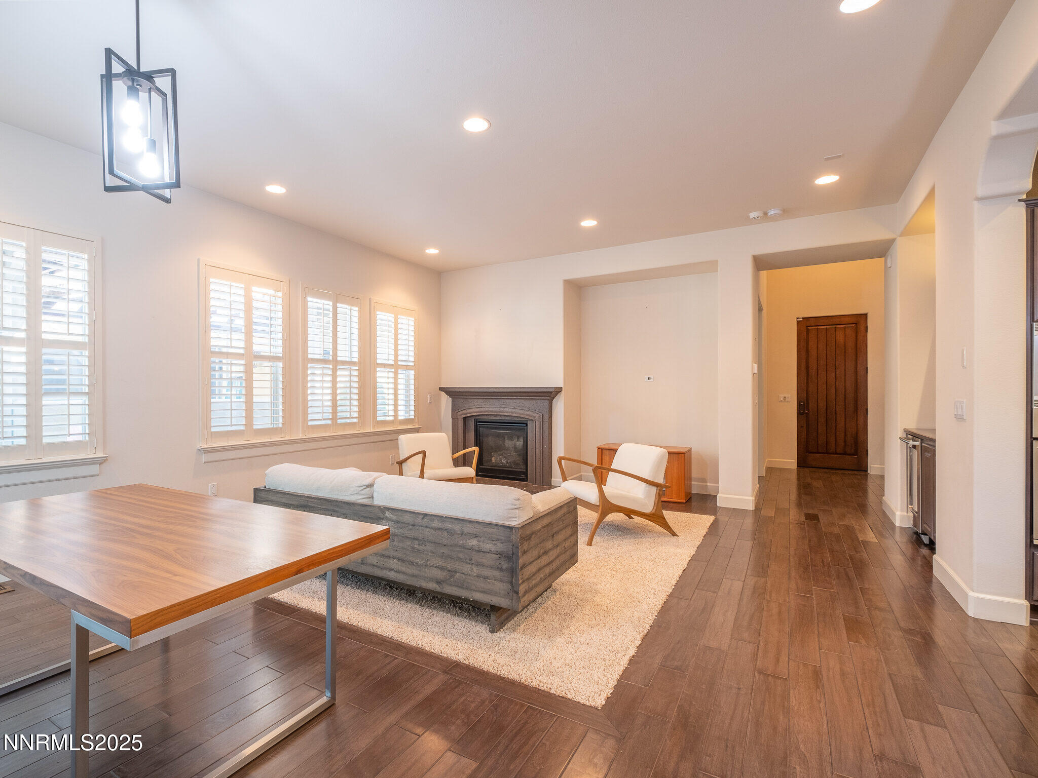 3985 San Donato Loop Reno, NV 89519 - Photo 5 of 29 a living room with a couch a dining table wooden floor and a fireplace