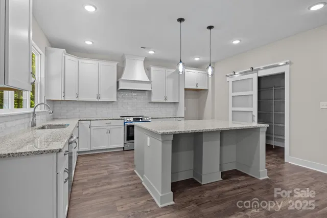 a large kitchen with granite countertop a sink a counter top stainless steel appliances and cabinets