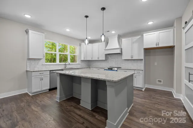 a kitchen with kitchen island granite countertop a sink a counter space appliances and cabinets
