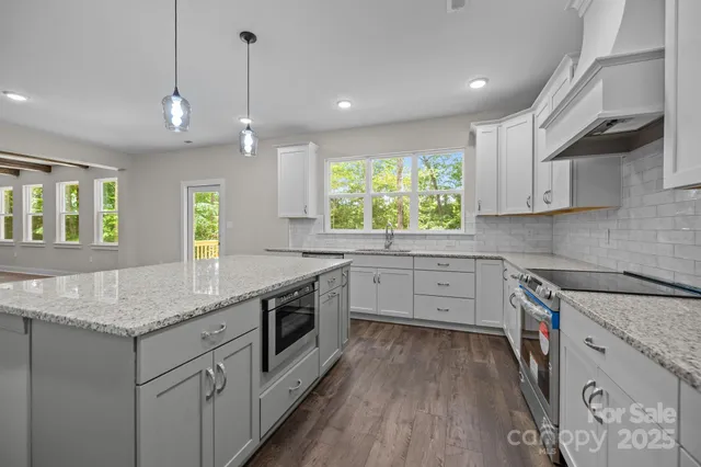 a kitchen with granite countertop a sink stainless steel appliances and cabinets