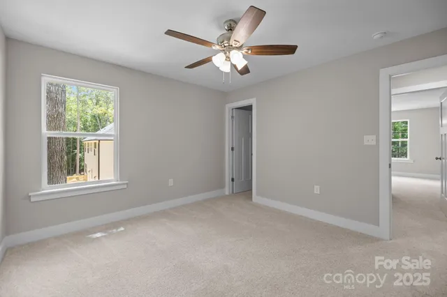 an empty room with window and ceiling fan