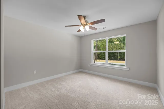 an empty room with a window and ceiling fan