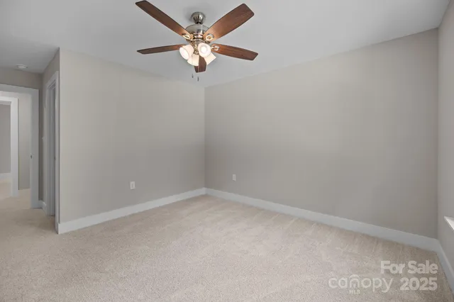 an empty room with a chandelier fan and windows
