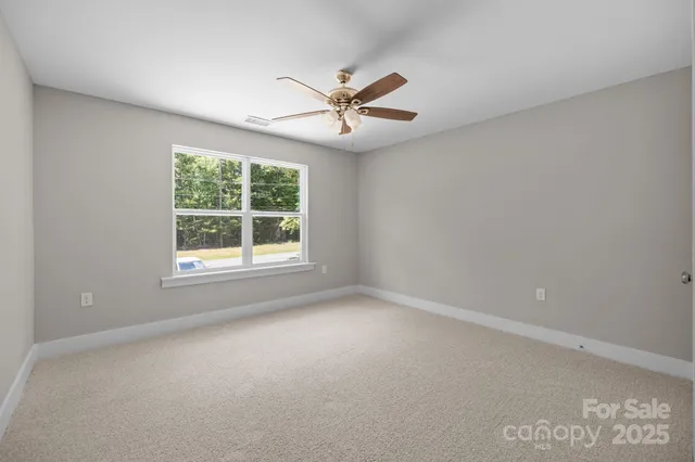an empty room with windows and ceiling fan