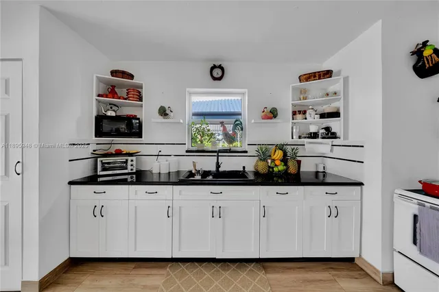 a kitchen with white cabinets and center island with wooden floor