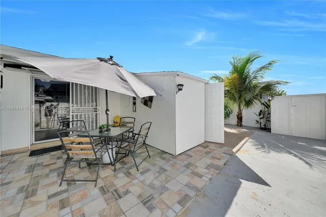 a patio with table and chairs and potted plants