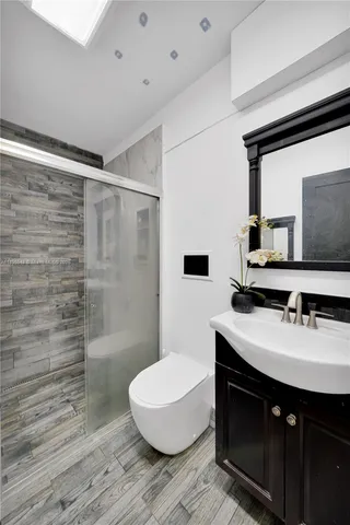 a bathroom with a sink a toilet a mirror and shower