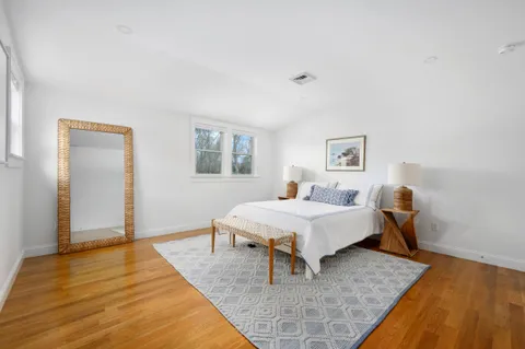 a spacious bedroom with a bed and wooden floor