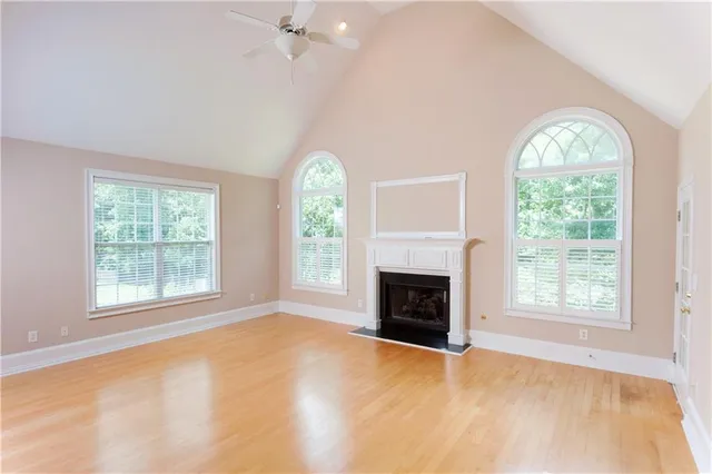an empty room with windows fireplace and wooden floor