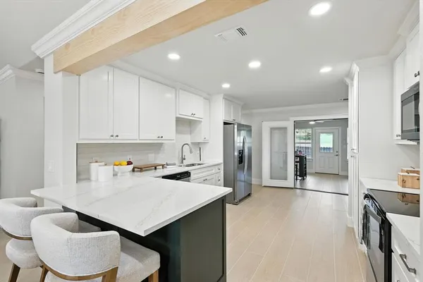 a kitchen with a refrigerator a sink dishwasher and white cabinets with wooden floor