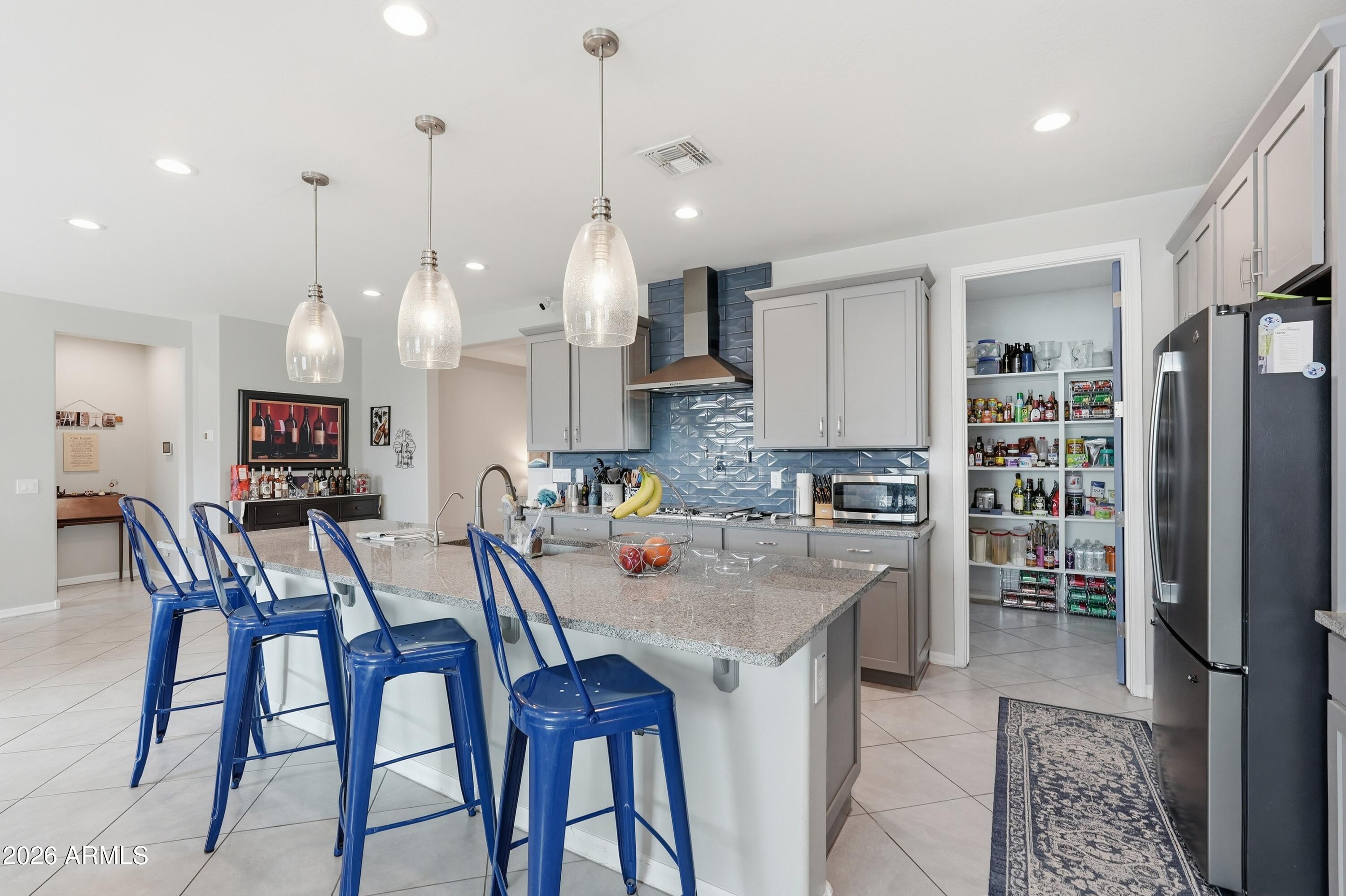 15727 West Madison Street Goodyear, AZ 85338 - Photo 12 of 41 an open kitchen with stainless steel appliances granite countertop a stove a refrigerator a oven a sink with a dining table and chairs
