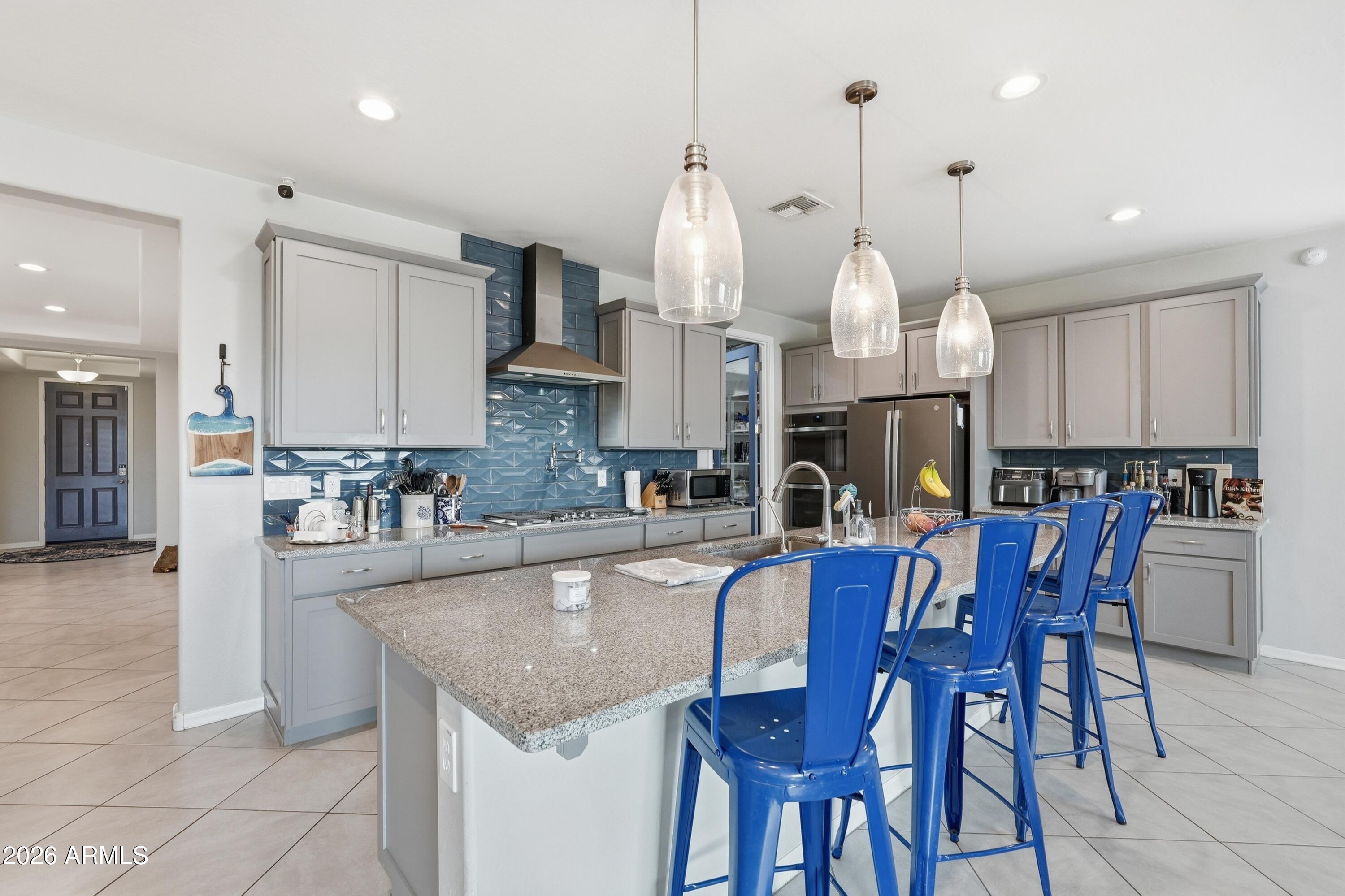 15727 West Madison Street Goodyear, AZ 85338 - Photo 13 of 41 a kitchen with granite countertop a table chairs stove a sink and a window