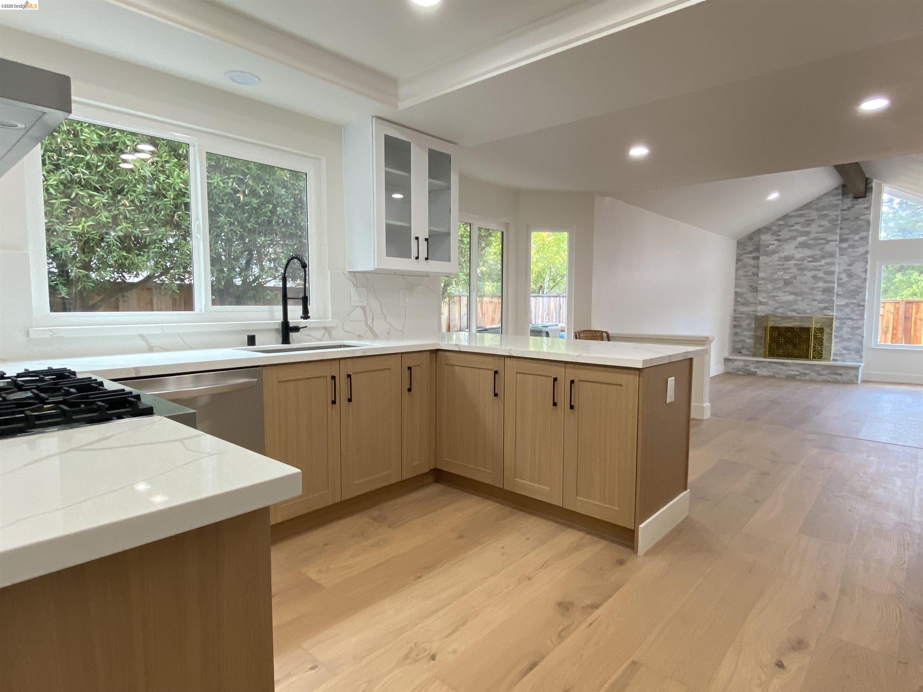 11 Paddock Court Pleasant Hill, CA 94523 - Photo 18 of 34 Kitchen with glass insert cabinets, a fireplace, decorative backsplash, vaulted ceiling, and a peninsula