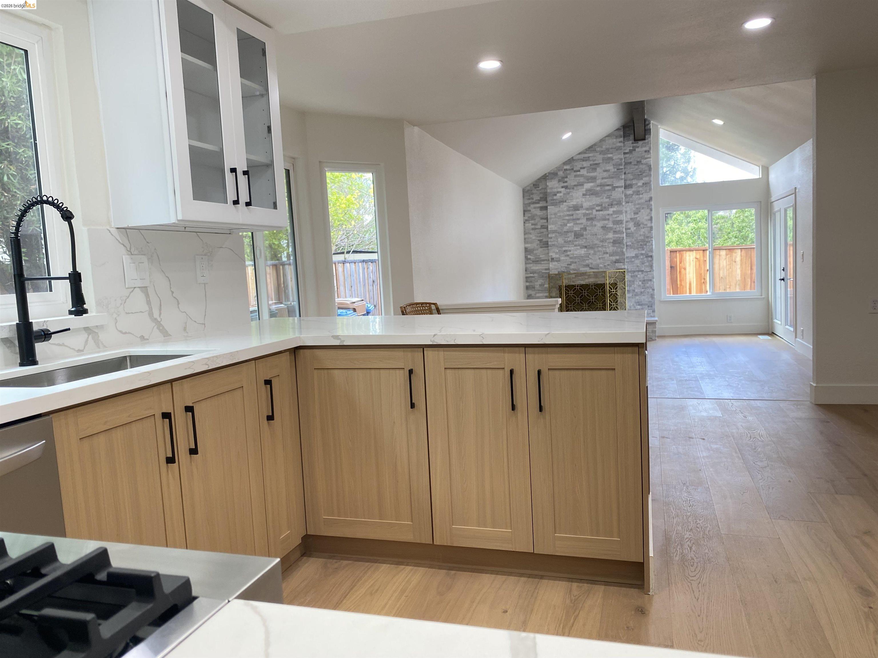 11 Paddock Court Pleasant Hill, CA 94523 - Photo 34 of 34 Kitchen with glass insert cabinets, open floor plan, decorative backsplash, light stone countertops, and light wood-type flooring