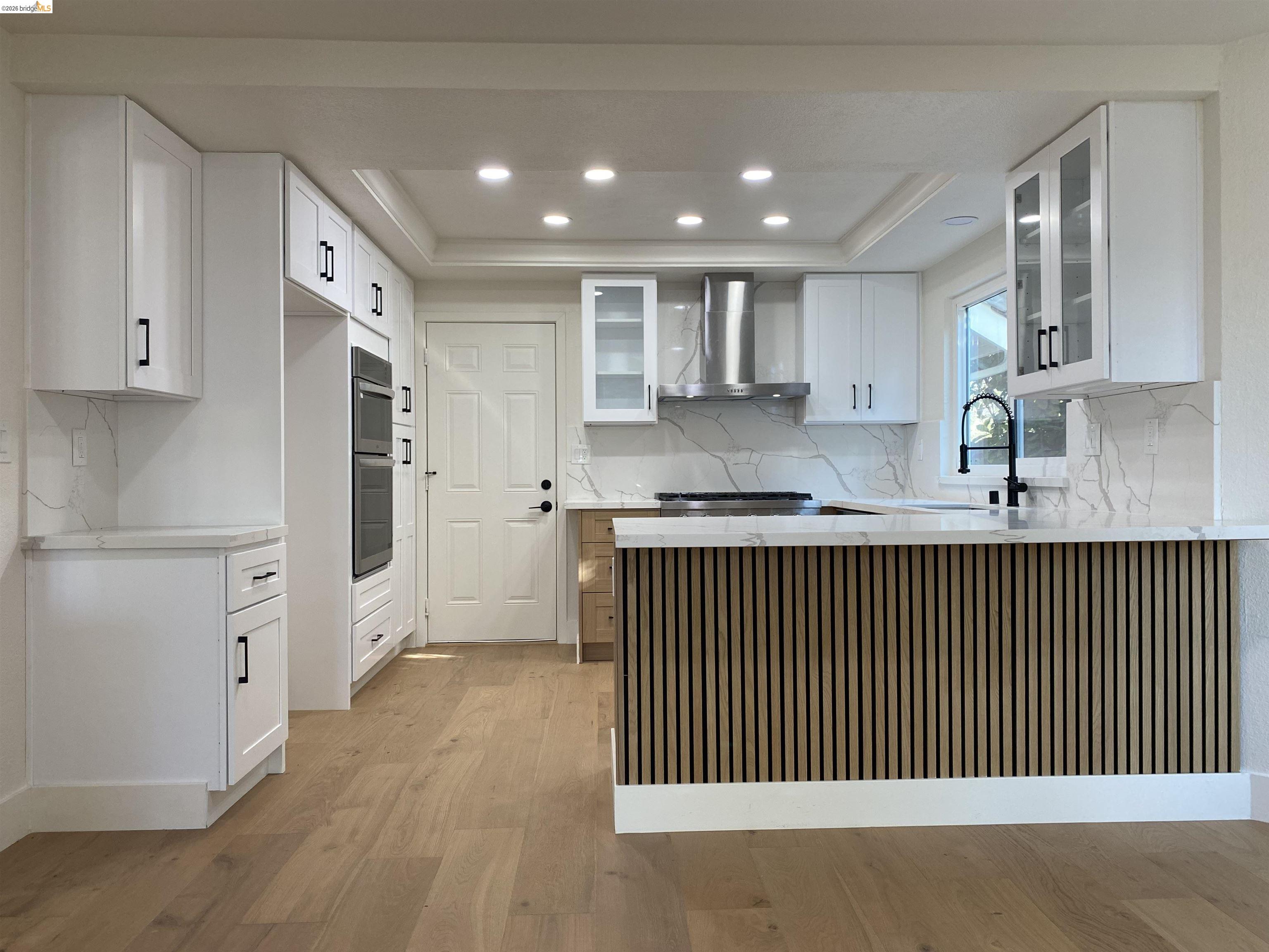 11 Paddock Court Pleasant Hill, CA 94523 - Photo 19 of 34 Kitchen with glass insert cabinets, white cabinetry, wall chimney exhaust hood, recessed lighting, and a raised ceiling