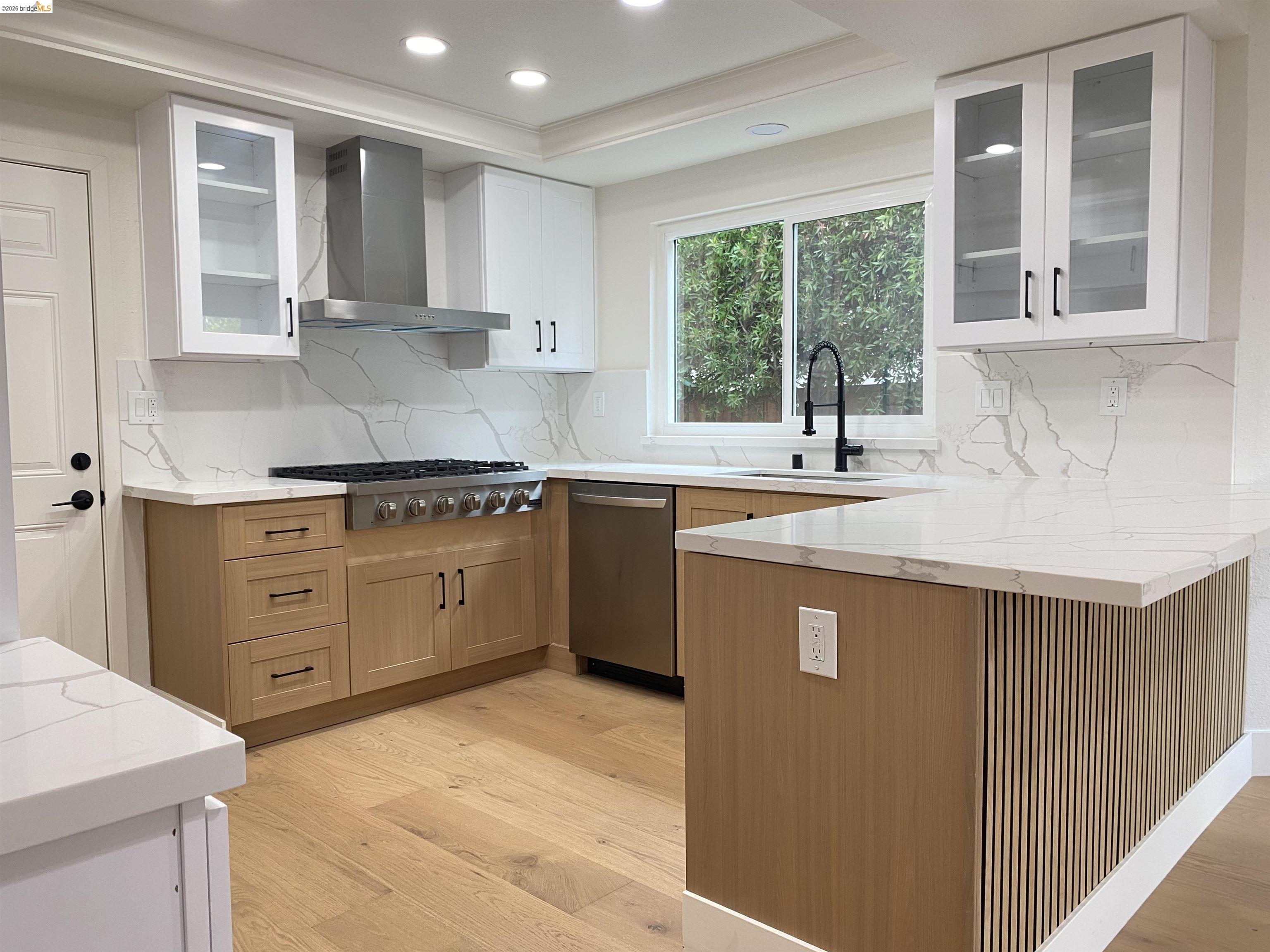 11 Paddock Court Pleasant Hill, CA 94523 - Photo 30 of 34 Kitchen featuring glass fronted cabinets, two tone cabinetry, light wood-style floors, a peninsula, and light stone countertops