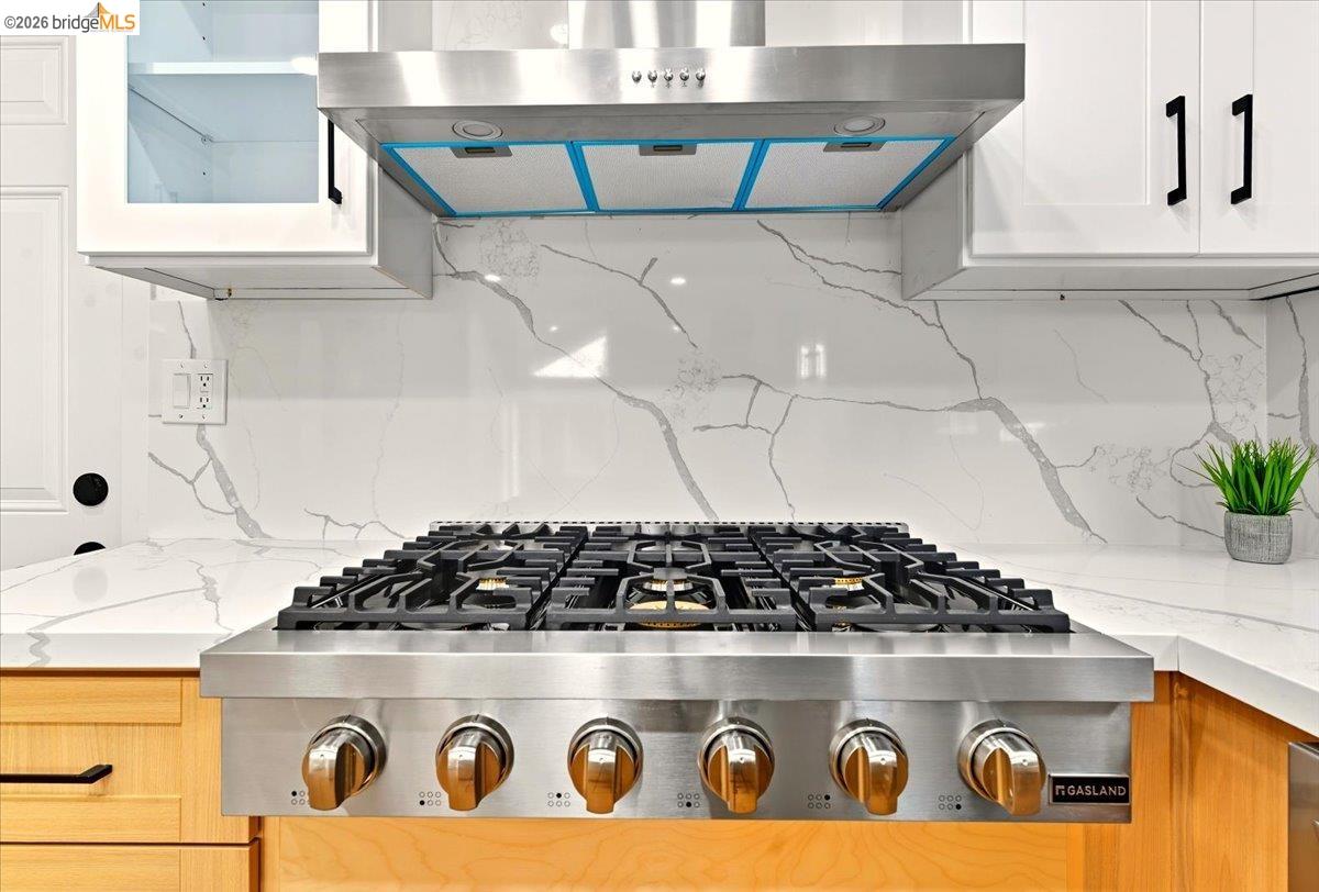 11 Paddock Court Pleasant Hill, CA 94523 - Photo 31 of 34 Kitchen view of under cabinet range hood, light stone counters, tasteful backsplash, and stainless steel gas stovetop