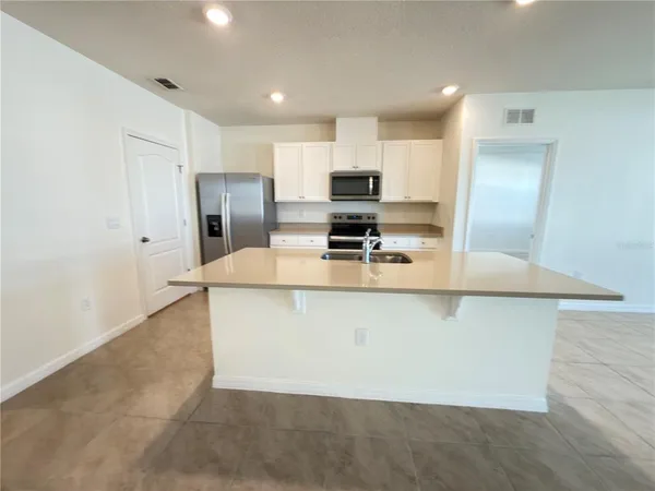 a large kitchen with stainless steel appliances a large counter top a stove a microwave a sink and refrigerator