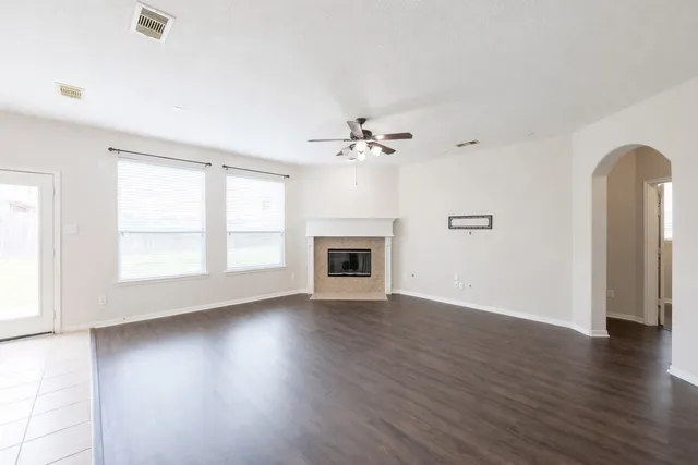 an empty room with wooden floor fireplace and windows