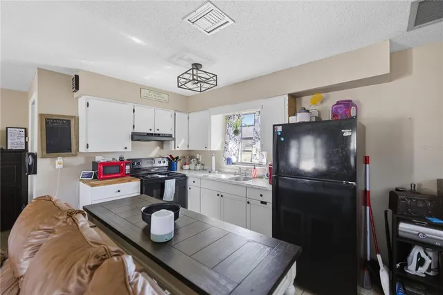 a kitchen with stainless steel appliances granite countertop a refrigerator sink stove and white cabinets