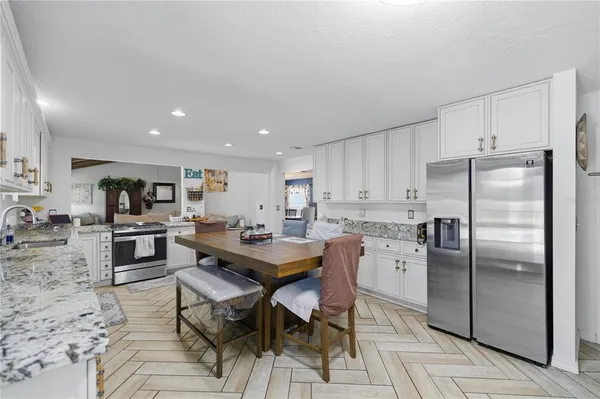 a kitchen with stainless steel appliances kitchen island granite countertop a refrigerator a stove a sink a table and chairs