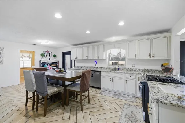 a kitchen with a dining table chairs sink and cabinets