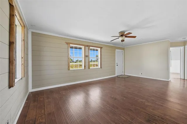 a view of an empty room with a window and wooden floor