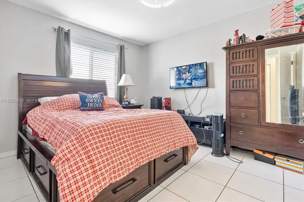 a bedroom with a bed a dresser and next to a window