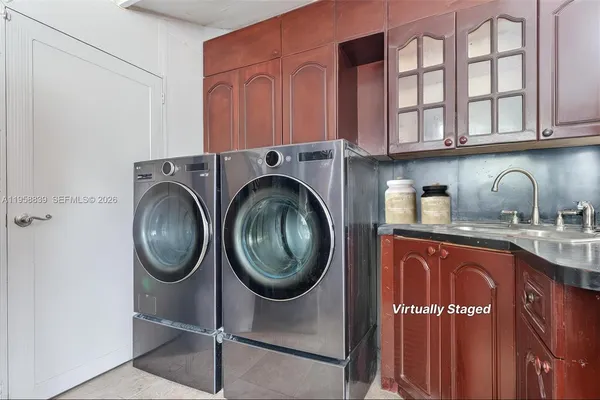 a utility room with sink dryer and cabinets