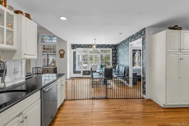 a kitchen with stainless steel appliances granite countertop a stove top oven a sink a refrigerator and white cabinets with wooden floor