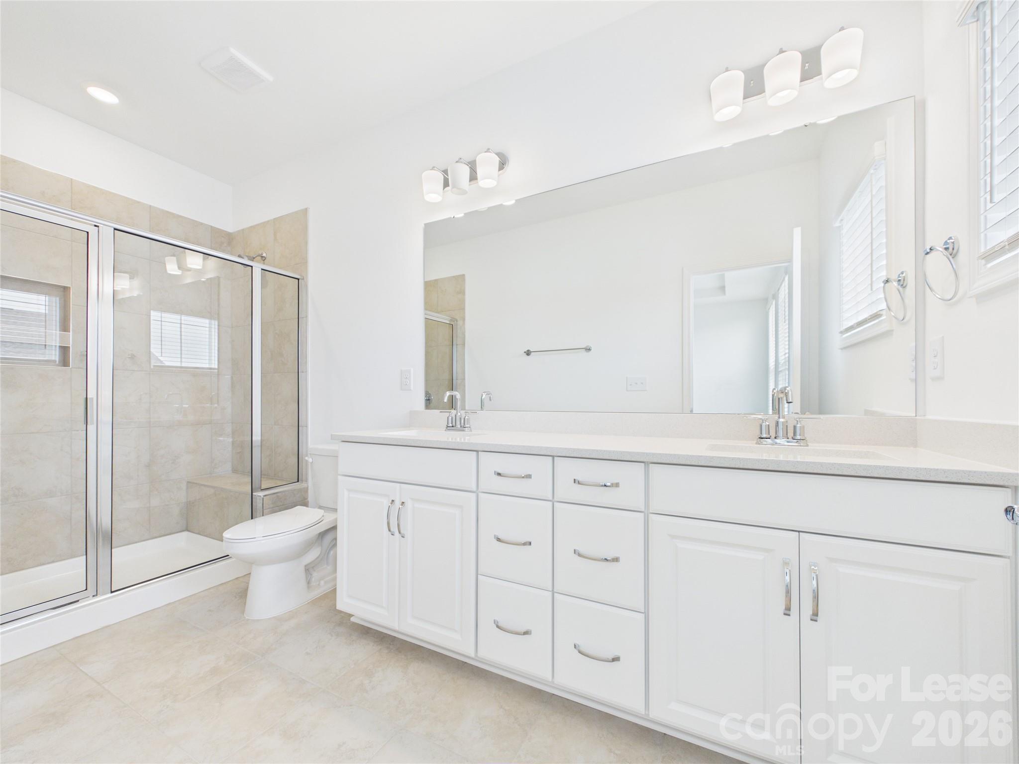 3013 Rexton Lane Charlotte, NC 28262 - Photo 15 of 27 a spacious bathroom with double sink a toilet a glass door a shower and a mirror
